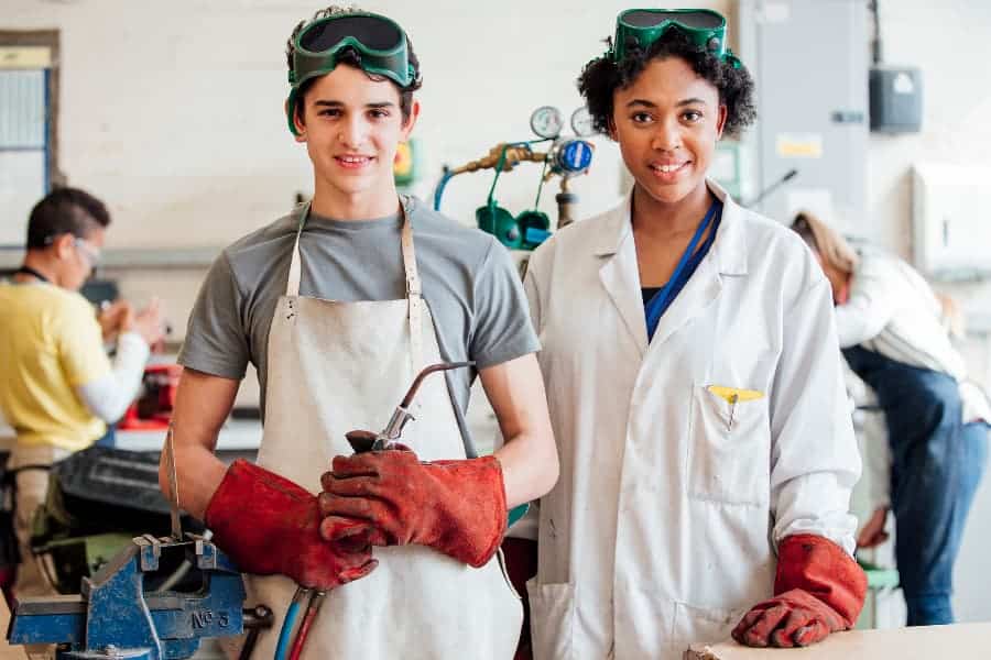 Student and teacher standing with welding gear in class