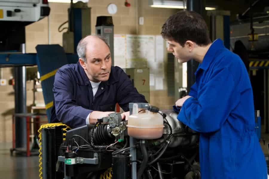 Mechanic and apprentice working on engine