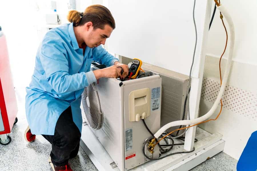 Air conditioner repair worker works on home unit