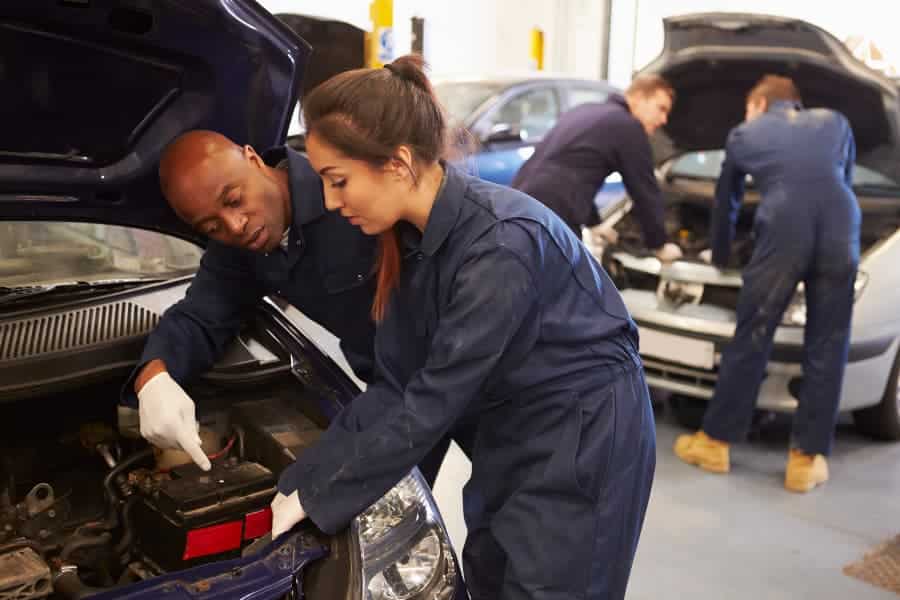 Teacher helping student training to be car mechanic