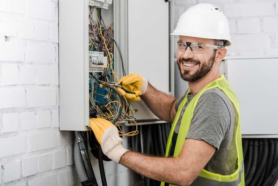 Electrician in protective workwear holding pliers while fixing cables
