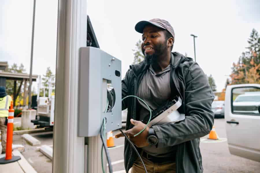 Person in hat working on electric vehicle charging station